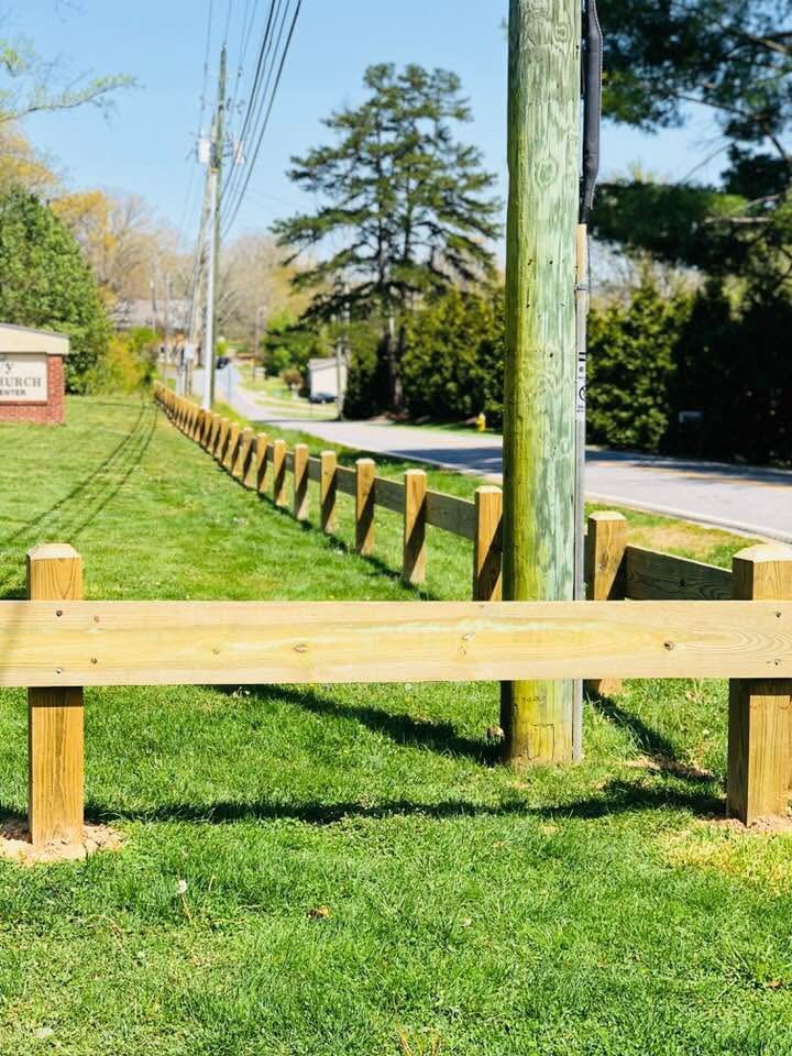 Timber post-and-rail guardrail along a roadside edge